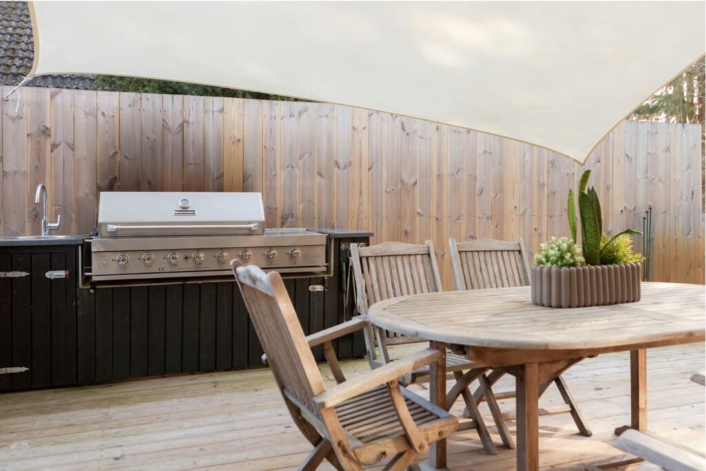 Uteplats med matbord och utekök i bakgrunden