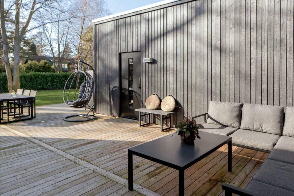 Uteplats med dörr till groventré på svart trähus