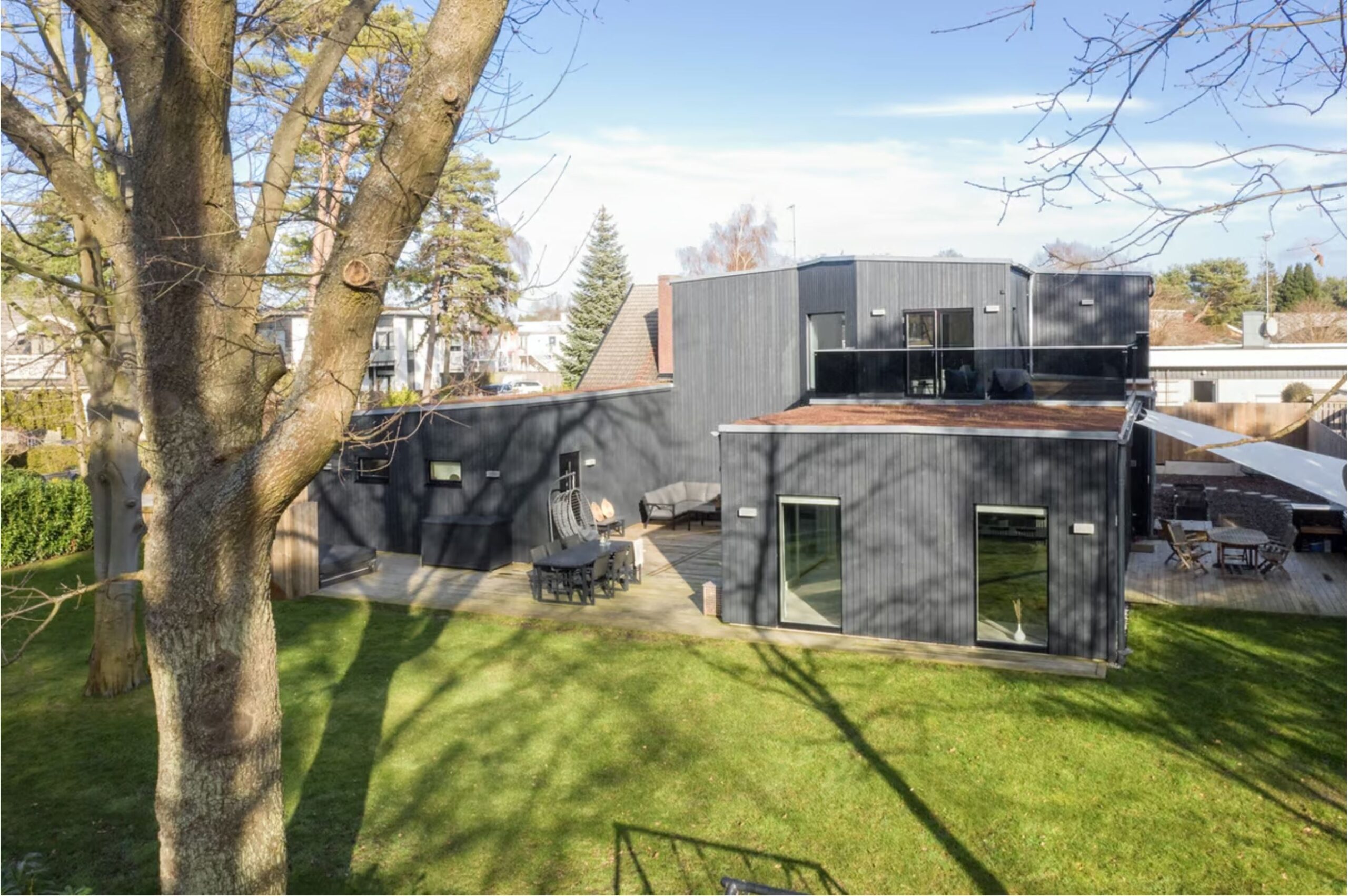 Svart trähus. Funkisstil med flera olika nivåer. Sedumtak.